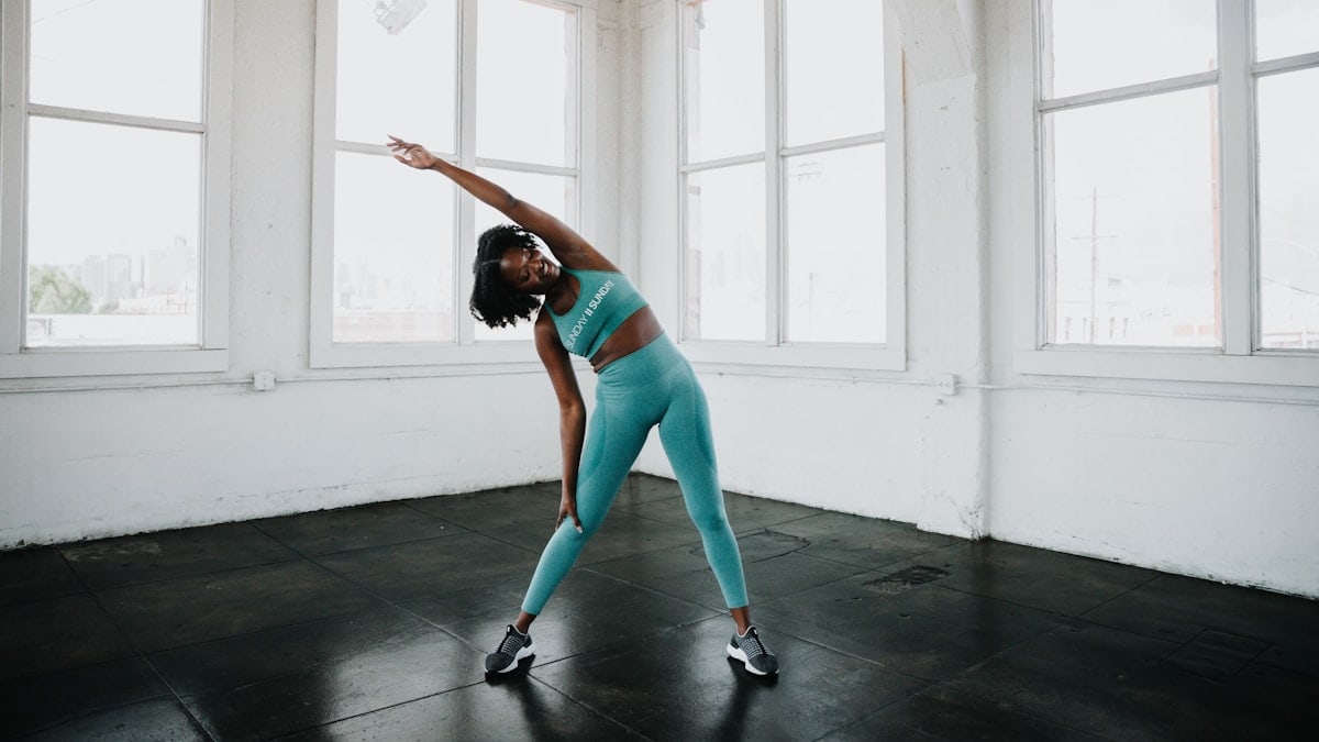 a woman in a blue sports bra top and leggings doing a yoga pose